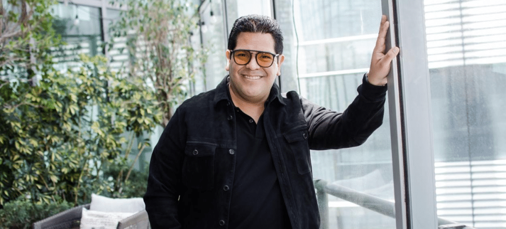 Persona llamada Federico Carlos Cerdas Ortiz con gafas y chaqueta negra junto a ventana y plantas al fondo.
