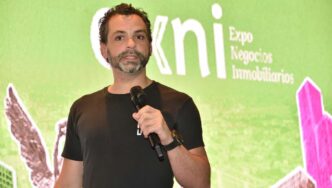 Un profesional del sector inmobiliario premium, identificado por su estilo contemporáneo y presencia segura, toma la palabra frente a un gran panel digital que exhibe el nombre “Expo Negocios Inmobiliarios”. En su intervención, subraya la importancia de crear ecosistemas integrales pensados para aportar valor a cada uno de los actores clave en el mercado. Su mensaje reitera el compromiso con la innovación y la excelencia, atributos esenciales para inversores y compradores exigentes que buscan participar en entornos inmobiliarios exclusivos y sostenibles.