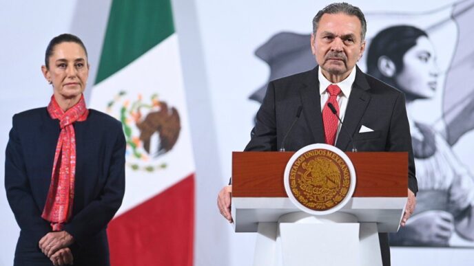 Un distinguido ejecutivo, ataviado con traje formal, se dirige al público desde un podio que exhibe el Escudo Nacional de México y el emblema de la AMPI, consolidando así la relevancia institucional del evento inmobiliario. A su lado, un representante acompaña la presentación, resaltando el compromiso conjunto con la excelencia. Como telón de fondo, ondea majestuosa la bandera mexicana junto a un mural en escala de grises que evoca liderazgo y visión. El entorno refleja los más altos estándares profesionales y proyecta seguridad jurídica y solidez patrimonial: atributos esenciales para inversores y compradores que exigen exclusividad en el sector inmobiliario premium.