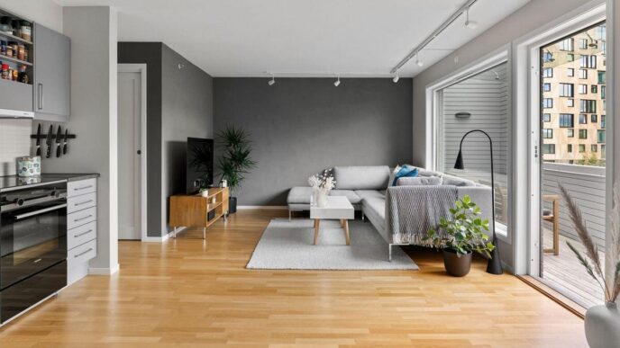 Descubra un cómodo espacio de residencia premium en CDMX: amplia sala de estar de concepto abierto, finamente diseñada con pisos de madera clara que realzan la luminosidad y amplitud del ambiente. El mobiliario contemporáneo incluye un elegante sofá gris y una mesa central minimalista, complementados por ventanas panorámicas que brindan acceso directo a un exclusivo balcón privado. Detalles decorativos como plantas interiores aportan frescura, mientras la moderna televisión empotrada marca el tono tecnológico del inmueble. La cocina integral, equipada con gabinetes en tonos grises mate, se integra visualmente para ofrecer funcionalidad y diseño superior—atributos ideales para inversionistas o compradores exigentes en busca de plusvalía y estilo urbano incomparable.