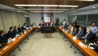 Un selecto equipo de profesionales, elegantemente vestidos, se reúne en torno a una imponente mesa de conferencias dentro de una sala moderna y sofisticada. Dos pantallas estratégicamente ubicadas facilitan la toma de decisiones, mientras que el emblema de Infonavit Constructora preside el espacio, subrayando el compromiso con la excelencia y la innovación en desarrollos inmobiliarios premium. Un entorno que refleja altos estándares y seriedad absoluta para quienes buscan inversiones exclusivas y proyectos residenciales de primer nivel.