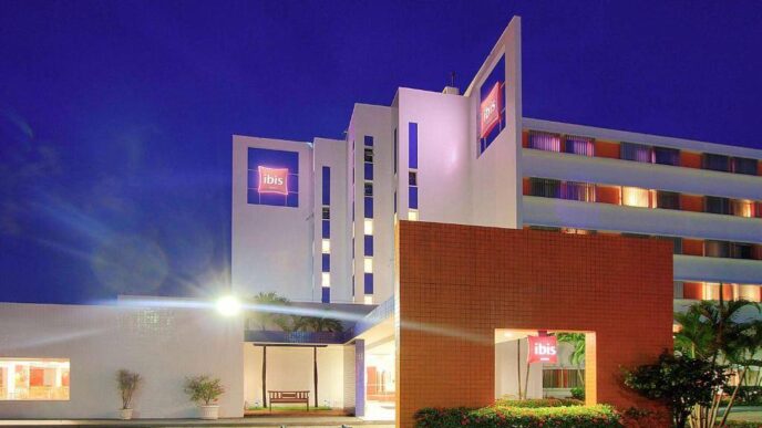 Edificio hotelero de múltiples niveles gestionado por Accor, con la reconocida insignia ibis en su fachada, destacado por su diseño moderno e iluminación arquitectónica nocturna que resalta su presencia urbana. La entrada principal, marcada por una elegante estructura naranja y rodeada de jardín cuidadosamente seleccionada, ofrece una bienvenida sofisticada y exclusiva. Esta propiedad representa una oportunidad excepcional para inversores o compradores que buscan activos inmobiliarios premium en el sector hotelero internacional.