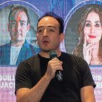 Un profesional del sector inmobiliario, vestido de manera sobria, interviene como ponente en una conferencia especializada sobre proptech. Mientras exponen su visión innovadora ante una audiencia de alto nivel, dos proyecciones a gran escala presentan a destacados referentes del sector, resaltando su experticia y protagonismo en la transformación digital del mercado inmobiliario premium. Esta escena refleja el liderazgo intelectual y la apuesta por tecnología de vanguardia que definen las tendencias más exclusivas para inversores y compradores exigentes.