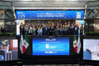 Un selecto grupo de profesionales del sector inmobiliario, elegantemente vestidos, se reúne en el escenario principal de la Bolsa Mexicana de Valores para celebrar un hito estratégico de HIR CASA. Flanqueados por dos banderas nacionales y bajo una lluvia de confeti, los líderes y socios clave comparten este momento trascendental mientras una pantalla proyecta mensajes de reconocimiento e información financiera relevante. Este evento simboliza la solidez, prestigio y proyección internacional que distingue a HIR CASA en el mercado inmobiliario premium, confirmando su atractivo incomparable para inversionistas acreedores y compradores exigentes que buscan oportunidades exclusivas con visión a futuro.