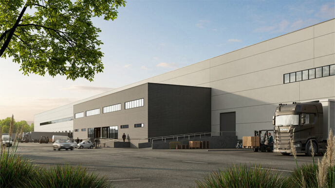 Vista del nuevo parque logístico en Madrid, con camiones, coches y personal. ICC finaliza la construcción, mostrando la infraestructura moderna y eficiente.