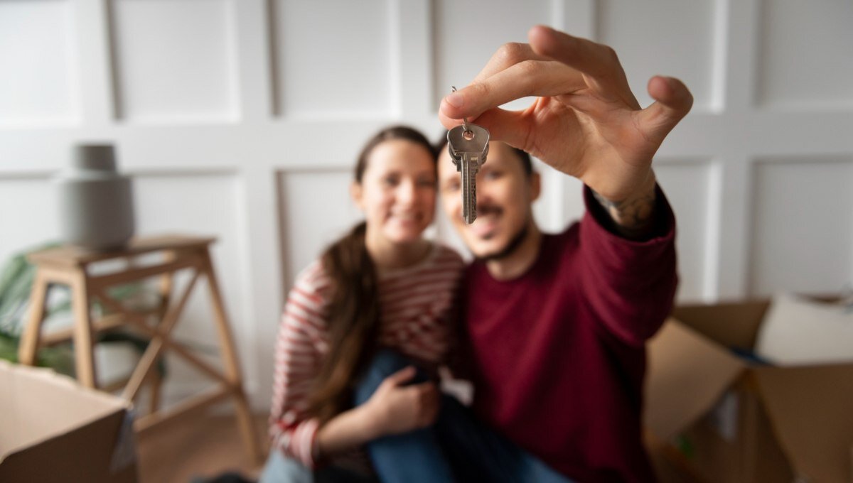 Una pareja sonriente sostiene un juego de llaves frente a la cámara, simbolizando la adquisición de su nueva residencia en México. Rodeados de mobiliario y cajas, celebran con satisfacción el acceso a una propiedad premium en un mercado inmobiliario de alta demanda y precios elevados. Este momento refleja las oportunidades únicas que ofrece el sector residencial exclusivo para quienes buscan invertir o establecerse en ubicaciones privilegiadas del país.