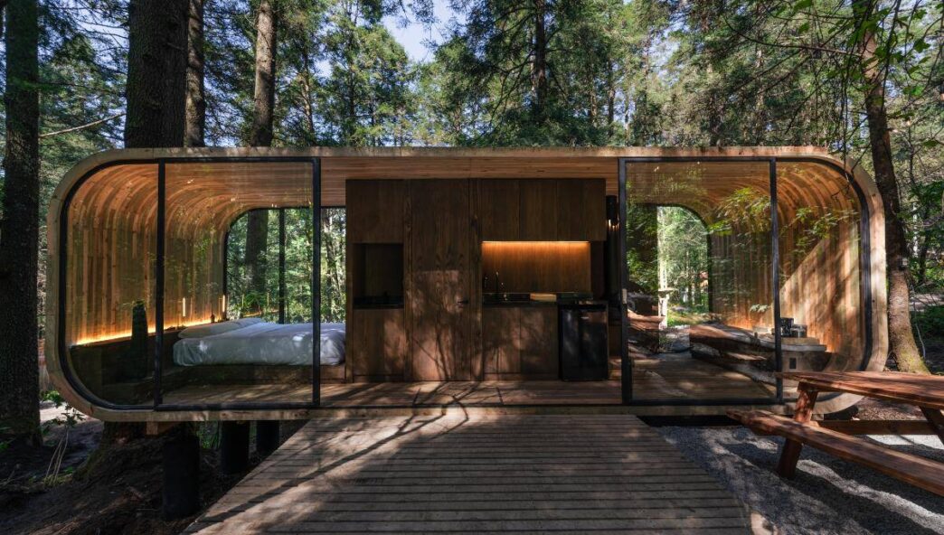 Esta exclusiva cabaña contemporánea, de diseño rectangular con elegantes esquinas redondeadas y amplios ventanales de vidrio, se integra armónicamente en un entorno elevado entre árboles maduros. Concebida para satisfacer las demandas del segmento premium en turismo sustentable y experiencias glamping de alto nivel, la propiedad ofrece interiores luminosos y funcionales que incluyen un dormitorio confortable y una cocineta totalmente equipada. En el exterior, una terraza privada con banco de madera sobre grava invita al descanso rodeado de naturaleza. Este activo representa una oportunidad excepcional para inversores o compradores que buscan distinguirse en el mercado inmobiliario sostenible sin renunciar al lujo ni al confort.