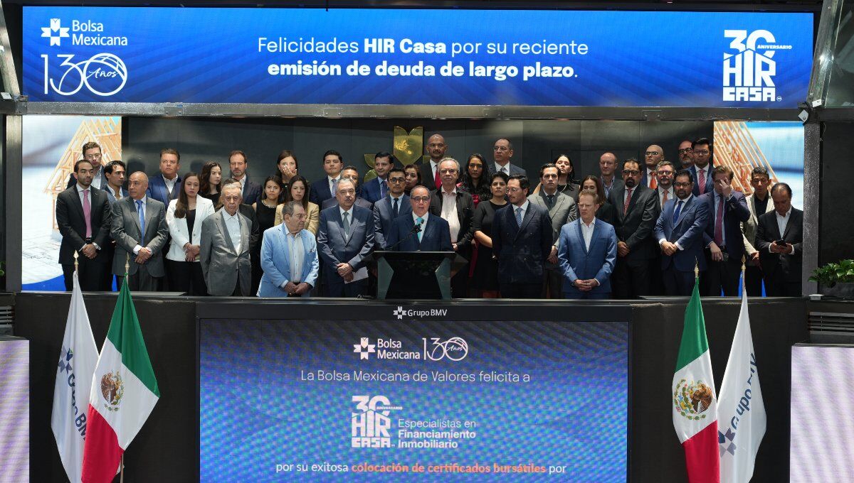 Un selecto grupo de líderes empresariales se reúne en el escenario principal de la Bolsa Mexicana de Valores para celebrar la exitosa colocación de deuda a largo plazo por parte de Hir Casa. La ocasión fue resaltada por mensajes institucionales que reconocieron este hito estratégico, proyectados en pantallas ubicadas sobre y debajo del grupo. Este logro refuerza la solidez financiera y la visión innovadora de Hir Casa dentro del segmento inmobiliario premium, destacando su capacidad para generar valor sostenible e impulsar oportunidades exclusivas para inversionistas y compradores exigentes.