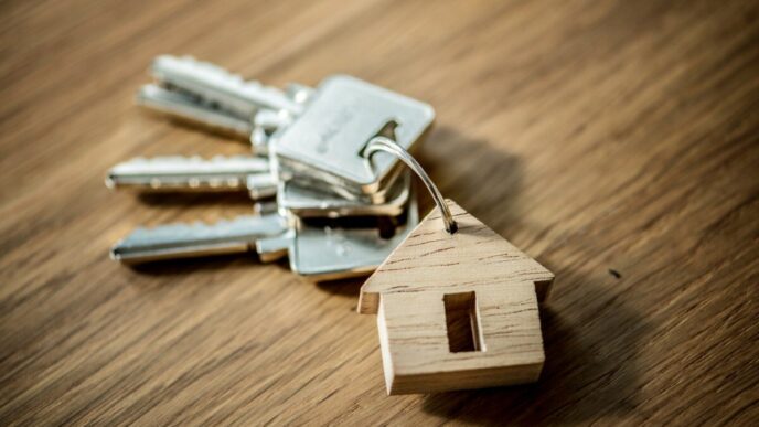 Juego de llaves metálicas en anilla, acompañado de un llavero en forma de casa elaborado en madera noble, elegantemente dispuesto sobre una superficie de fina madera. Un símbolo distintivo que representa acceso exclusivo a propiedades premium, diseñado para reflejar el estilo y la seguridad que buscan inversores y compradores exigentes en el sector inmobiliario de alto nivel.