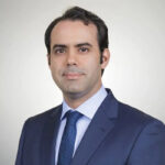 Un hombre viste un sofisticado traje azul marino, camisa celeste y corbata azul con discretos detalles, proyectando la elegancia y el refinamiento característicos de las Branded Residences en destinos premium como Baja. Esta imagen personifica el alto nivel de distinción y estilo de vida que buscan los inversores y compradores más exigentes en el sector inmobiliario de lujo.