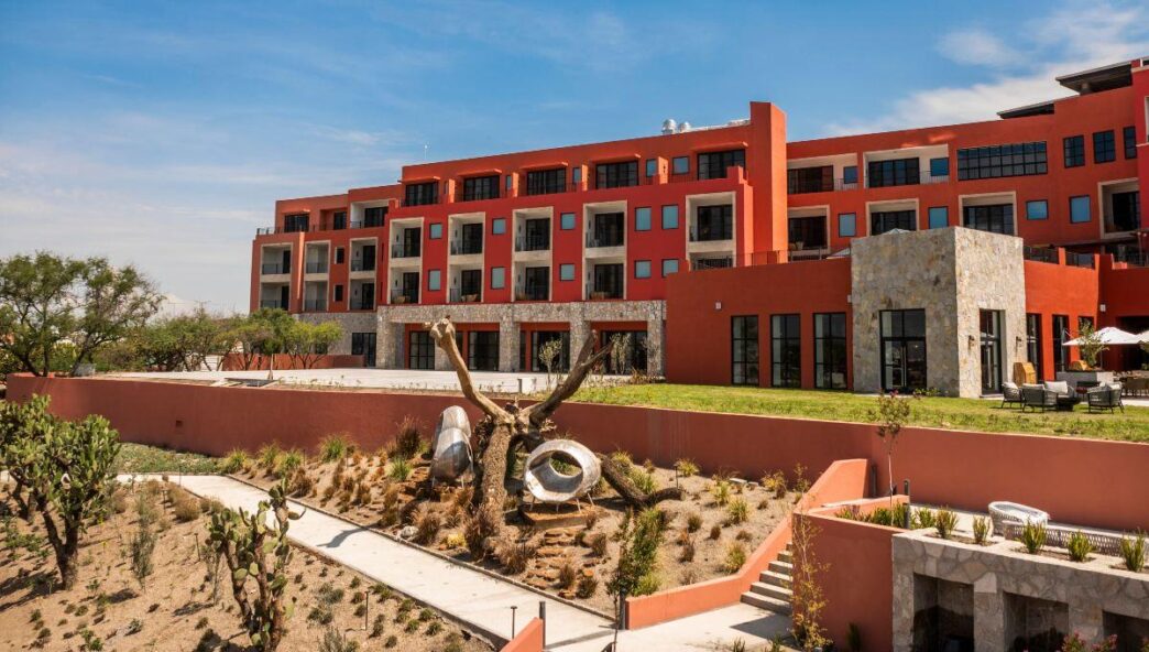 Este exclusivo edificio de diseño contemporáneo, de varios niveles y estructura en tonos rojo y beige, destaca por sus amplios ventanales y terrazas privadas que favorecen la luminosidad natural y las vistas panorámicas. Ubicada en Pueblo Bonito Vantage, la propiedad se integra a un sofisticado entorno paisajístico que incorpora un elegante jardín seco boutique, una propuesta única de estilo con cactus seleccionados, formaciones rocosas cuidadosamente dispuestas y una escultura arbórea distintiva. Todo ello bajo el marco de cielos despejados, creando un ambiente inigualable ideal para clientes exigentes en busca de inversión inmobiliaria premium o una residencia exclusiva con carácter y distinción.