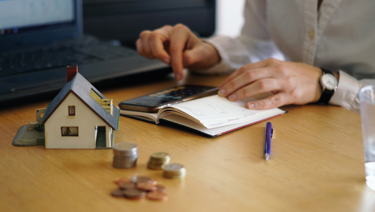 Profesional revisando proyecciones financieras y estrategias de inversión en un entorno equipado con modelos arquitectónicos, monedas representativas del capital y tecnología de punta. Esta escena refleja el análisis riguroso y la planificación estratégica indispensables para el éxito de proyectos inmobiliarios premium y desarrollos hoteleros exclusivos. Un enfoque orientado a maximizar el retorno sobre la inversión, asegurando oportunidades sólidas y rentables en el sector inmobiliario de alta gama.