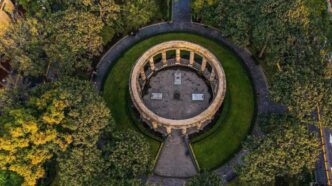 Vista aérea de un emblemático monumento circular de piedra, rodeado por jardines meticulosamente cuidados y frondosos árboles en el corazón del Centro Histórico de Guadalajara. Este espacio, recientemente renovado, se conecta armónicamente a través de elegantes senderos pavimentados que se dirigen al centro del monumento. Ubicación privilegiada y diseño arquitectónico icónico que realzan el valor patrimonial e inmobiliario, convirtiéndolo en un entorno ideal para inversiones exclusivas o proyectos residenciales premium.
