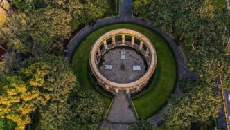 Vista aérea de un emblemático monumento circular de piedra, rodeado por jardines meticulosamente cuidados y frondosos árboles en el corazón del Centro Histórico de Guadalajara. Este espacio, recientemente renovado, se conecta armónicamente a través de elegantes senderos pavimentados que se dirigen al centro del monumento. Ubicación privilegiada y diseño arquitectónico icónico que realzan el valor patrimonial e inmobiliario, convirtiéndolo en un entorno ideal para inversiones exclusivas o proyectos residenciales premium.