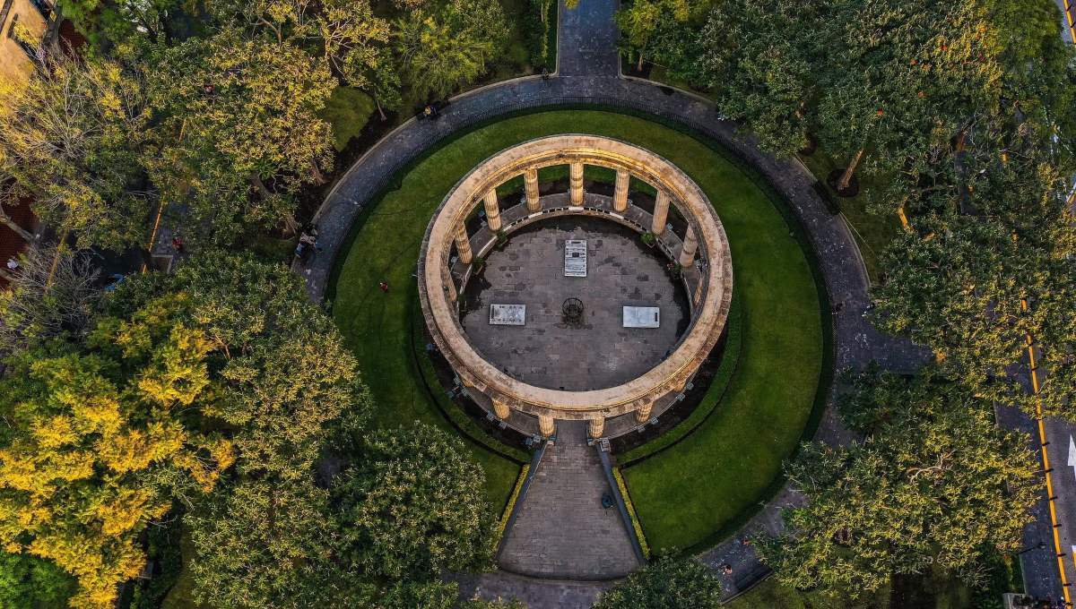 Vista aérea de un emblemático monumento circular de piedra, rodeado por jardines meticulosamente cuidados y frondosos árboles en el corazón del Centro Histórico de Guadalajara. Este espacio, recientemente renovado, se conecta armónicamente a través de elegantes senderos pavimentados que se dirigen al centro del monumento. Ubicación privilegiada y diseño arquitectónico icónico que realzan el valor patrimonial e inmobiliario, convirtiéndolo en un entorno ideal para inversiones exclusivas o proyectos residenciales premium.