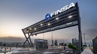 Acceso principal a parque industrial de alta gama, con un imponente letrero negro FINSA iluminado, caseta de seguridad equipada, barreras automáticas y vialidades completamente pavimentadas. Esta infraestructura moderna refleja los más altos estándares inmobiliarios para 2024 y subraya el compromiso con la Certificación LEED, garantizando eficiencia, sostenibilidad y máxima seguridad para inversionistas y compradores que exigen excelencia.