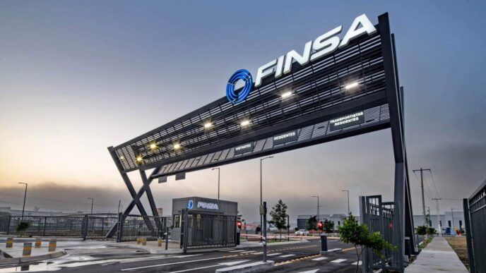 Acceso principal a parque industrial de alta gama, con un imponente letrero negro FINSA iluminado, caseta de seguridad equipada, barreras automáticas y vialidades completamente pavimentadas. Esta infraestructura moderna refleja los más altos estándares inmobiliarios para 2024 y subraya el compromiso con la Certificación LEED, garantizando eficiencia, sostenibilidad y máxima seguridad para inversionistas y compradores que exigen excelencia.