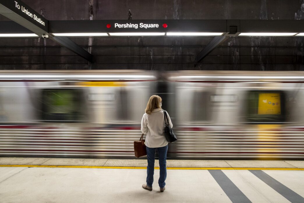 Ciudad con transporte público: Mujer espera el tren en la estación Pershing Square. Movilidad urbana en Los Ángeles, California.