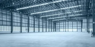 Empty warehouse interior with high ceilings and metal structure.