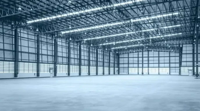 Empty warehouse interior with high ceilings and metal structure.
