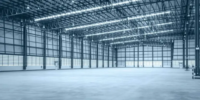 Empty warehouse interior with high ceilings and metal structure.