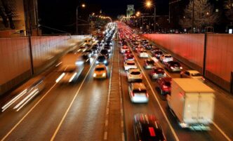 Tráfico nocturno en Reino Unido: congestión vehicular urbana con estelas luminosas de coches, reflejo de modernización del transporte y acuerdo CCS.