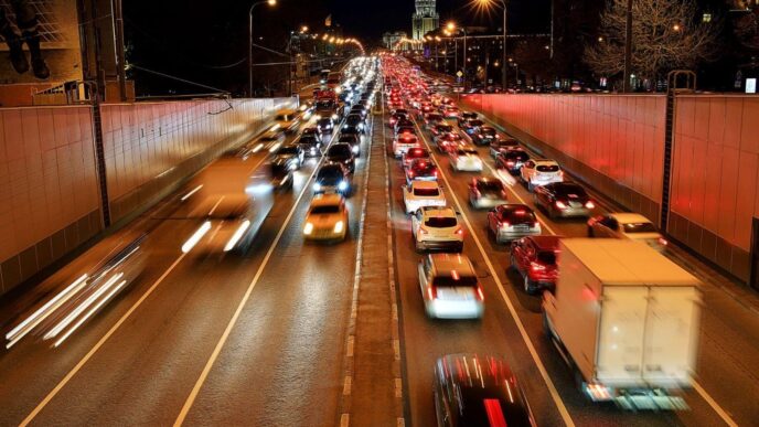 Tráfico nocturno en Reino Unido: congestión vehicular urbana con estelas luminosas de coches, reflejo de modernización del transporte y acuerdo CCS.