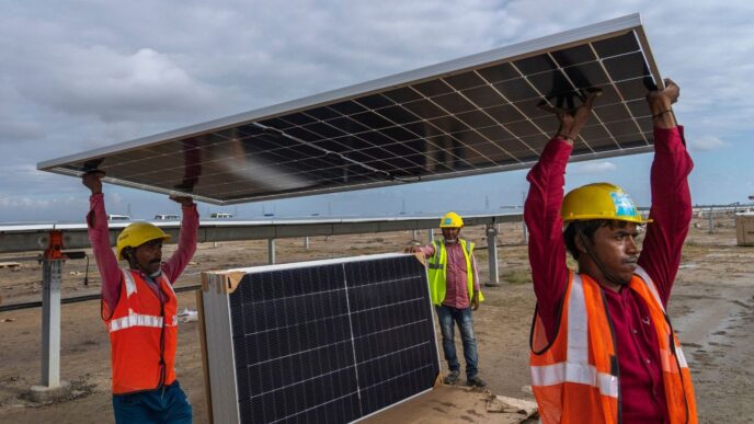 Trabajadores instalan paneles solares en Khavda, impulsando la energía renovable de Adani Green Energy. Parque solar en construcción. Energía limpia.