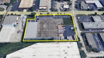 Vista aérea de inmueble industrial en Chicago, resaltado en amarillo. Adquisición por Brennan Investment Group. Camiones y estacionamiento visibles.