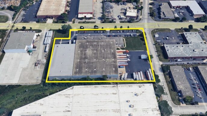 Vista aérea de inmueble industrial en Chicago, resaltado en amarillo. Adquisición por Brennan Investment Group. Camiones y estacionamiento visibles.