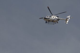 Helicóptero blanco y azul volando en el cielo, posible taxi aéreo para el AIFA. Transporte aéreo moderno y eficiente en México. AMLO impulsa AIFA.