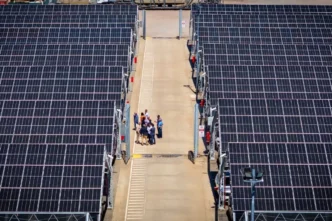Vista aérea del nuevo parque solar comunitario en Córdoba, Argentina. Paneles solares alineados con personas para su inauguración. Energía renovable y sostenible.