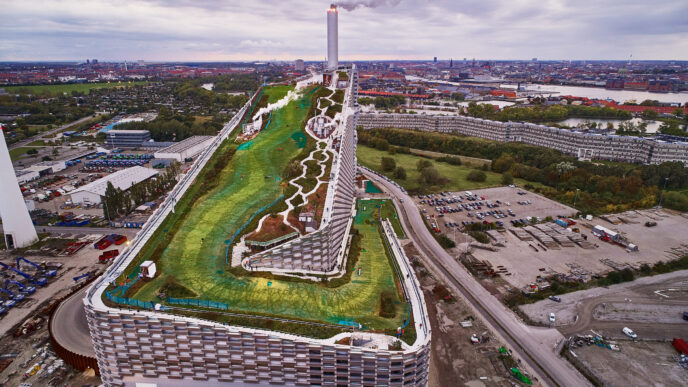 Vista aérea de Copenhague con edificio innovador que integra arquitectura y naturaleza, clave en la lucha contra el cambio climático, con chimenea.