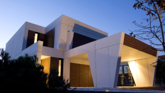 Fachada moderna de hotel Camino Real: diseño geométrico en blanco y madera. Inversión en renovación visible en cada detalle arquitectónico.