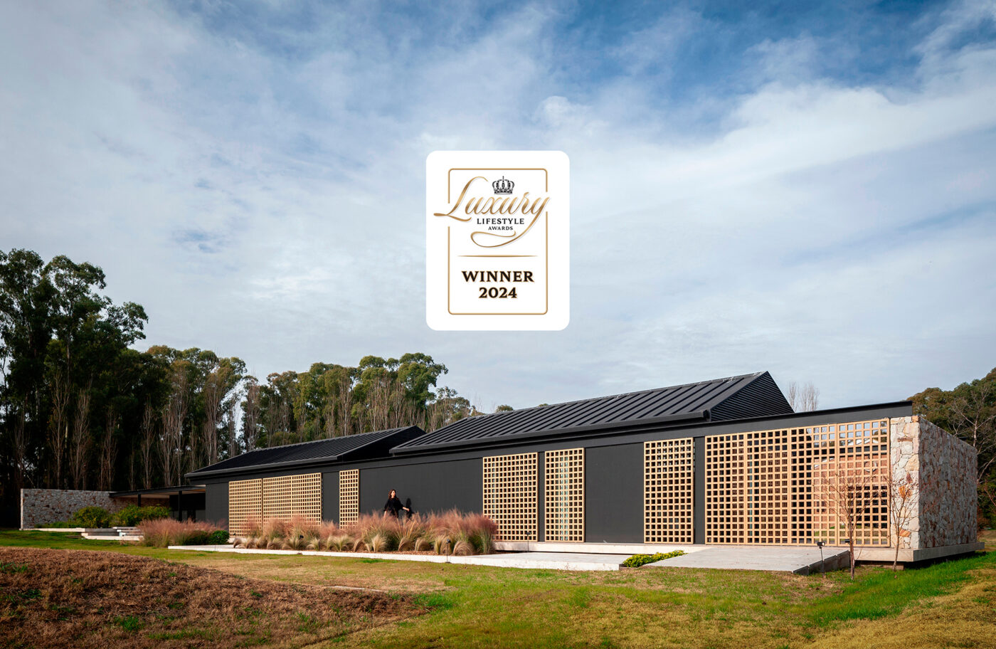 Casa Orilla, residencia de lujo ganadora 2024. Arquitectura moderna con detalles en madera y piedra. Diseño premiado de estilo contemporáneo.