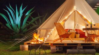 Glamping de lujo en Nuevo León: Tienda iluminada con fogata, sillas y mesa con vino. Experiencia hotelera única en la naturaleza para 2024.