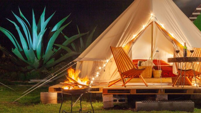 Glamping de lujo en Nuevo León: Tienda iluminada con fogata, sillas y mesa con vino. Experiencia hotelera única en la naturaleza para 2024.
