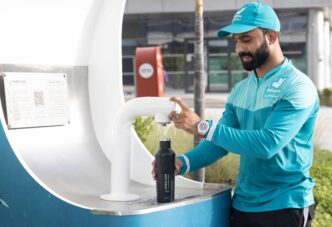 Hombre de Deliveroo rellena botella reutilizable en fuente Dubai Can. Iniciativa para reducir plástico, como ATELIER de Hoteles promueve.