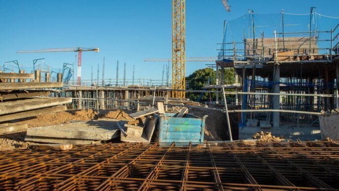 Construcción de casas sostenibles en España: vista de una obra con grúas y materiales, reflejando el auge de la demanda eco-friendly.