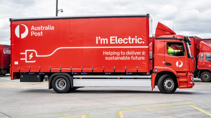 Camión eléctrico de Australia Post. Diseño rojo con logo y enchufe, promoviendo un futuro sostenible y cero carbono. Innovación en transporte.