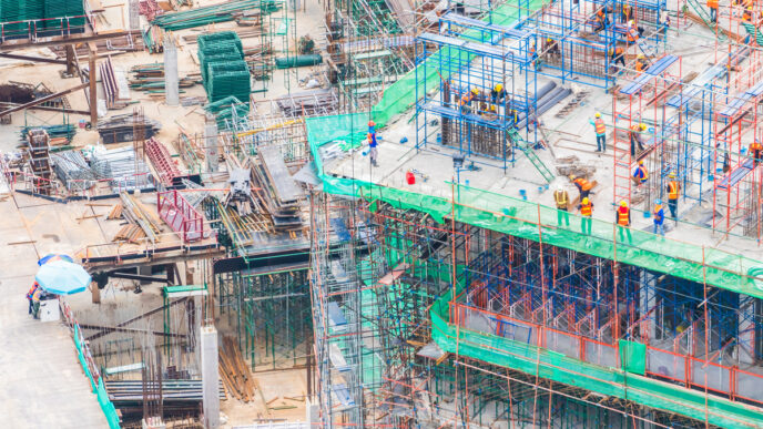 Vista aérea de construcción con andamios y trabajadores, impulsando la economía circular en la construcción con Cemex y Fundación Ellen MacArthur.