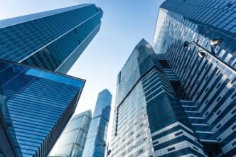 Vista ascendente de edificios de oficinas modernos con fachada de cristal. Sector de oficinas en avance, recuperación estimada hasta 2023.