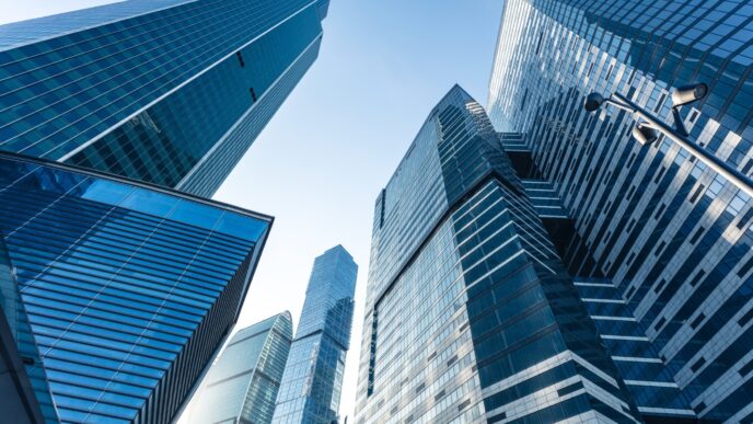 Vista ascendente de edificios de oficinas modernos con fachada de cristal. Sector de oficinas en avance, recuperación estimada hasta 2023.