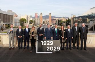 Grupo posa en Montjuïc, Barcelona, para la renovación del recinto. Inversión de 174 mde, torres gemelas al fondo. Anuncio de 1929-2029.
