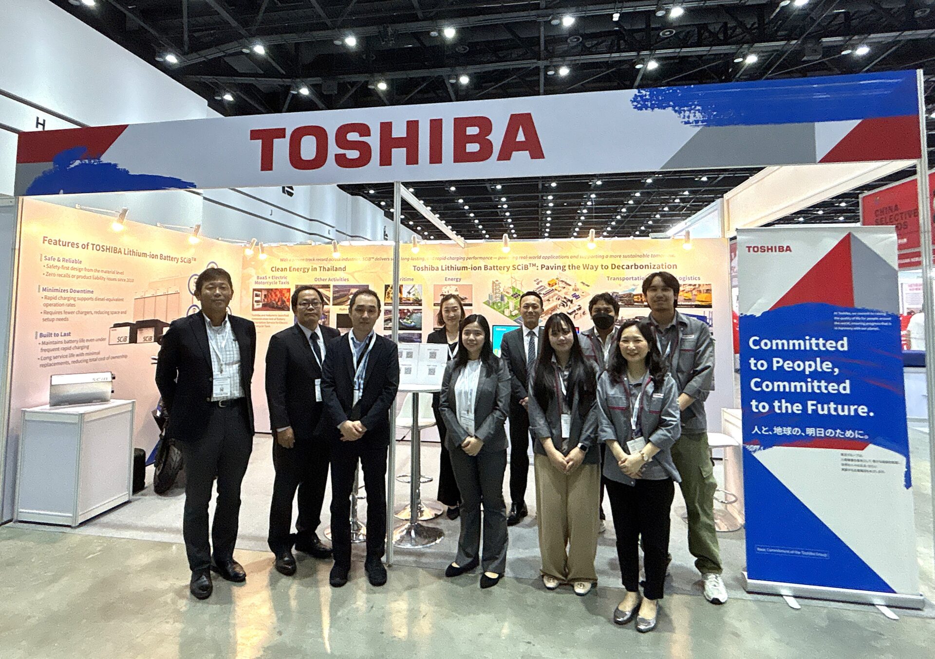 Grupo frente al stand de Toshiba SCiB, mostrando innovación en baterías de litio para energía sostenible y un futuro comprometido con la gente.