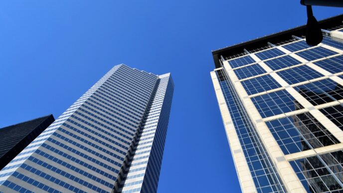 Edificios modernos con ventanas reflectantes bajo un cielo azul claro. Arquitectura urbana para BIPV Enabler, herramienta tecnológica.