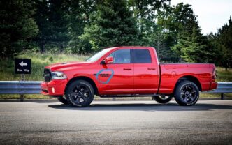 Camioneta roja Ram 1500 en Saltillo, Coahuila. Borgwarner expande operaciones con nuevo complejo. Vista lateral del vehículo en carretera con señal de tráfico.