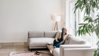 speakers/headshot
Mujer reflexiona sentada en un sofá cerca de la ventana. Pensando en bienes raíces e hipotecas en México.