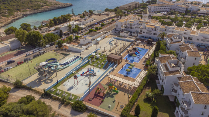 Vista aérea de resort con piscinas y juegos. Caldea anuncia hotel en España, complejo cuatro estrellas. Destino ideal para vacaciones familiares.