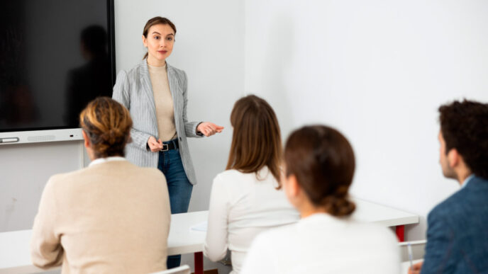 Instructora en el 9º Foro Inmobiliario AMPI Riviera Maya, capacitando sobre el sector. Mujer explicando frente a pantalla y asistentes.